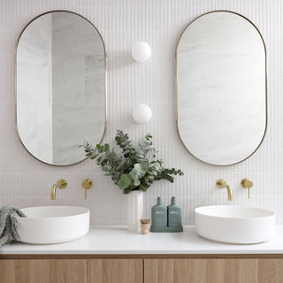 Bathroom with double vanity, oval mirrors, and decorative elements.