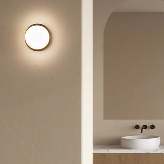 Bode Round Wall/Ceiling Light by Lighting Republic in Old Brass mounted on textured wall in warm modern interior