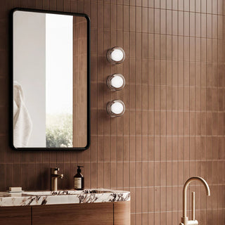 Three Orb Sur Ribbed Wall Lights installed beside a modern bathroom mirror with warm tiled wall finish