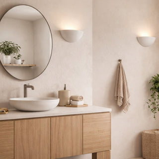 Bathroom interior with wooden vanity, round mirror, and plants.